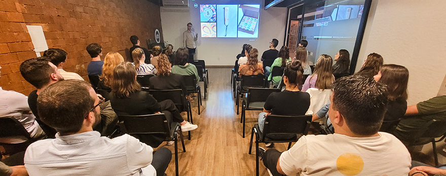 Imagem ilustrativa com fotografia de um grupo de 40 pessoas sentadas em um auditório e design: Talks670